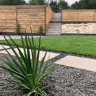 Terraced Westlake Hills backyard with stepping stones, gravel, sod, concrete steps, and a horizontal slat fence