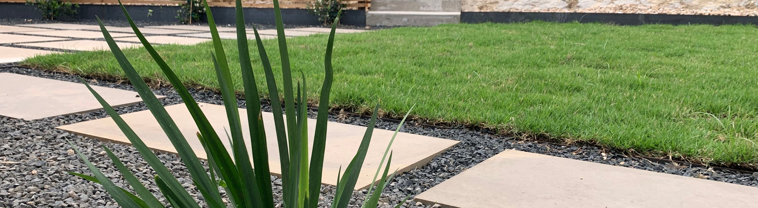 Terraced Westlake Hills backyard with stepping stones, gravel, sod, concrete steps, and a horizontal slat fence