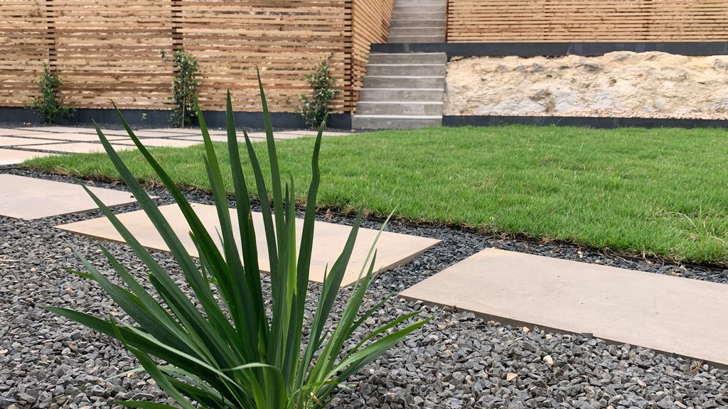 Designed Westlake Hills terrace with concrete steps and gravel managing a sloped grade