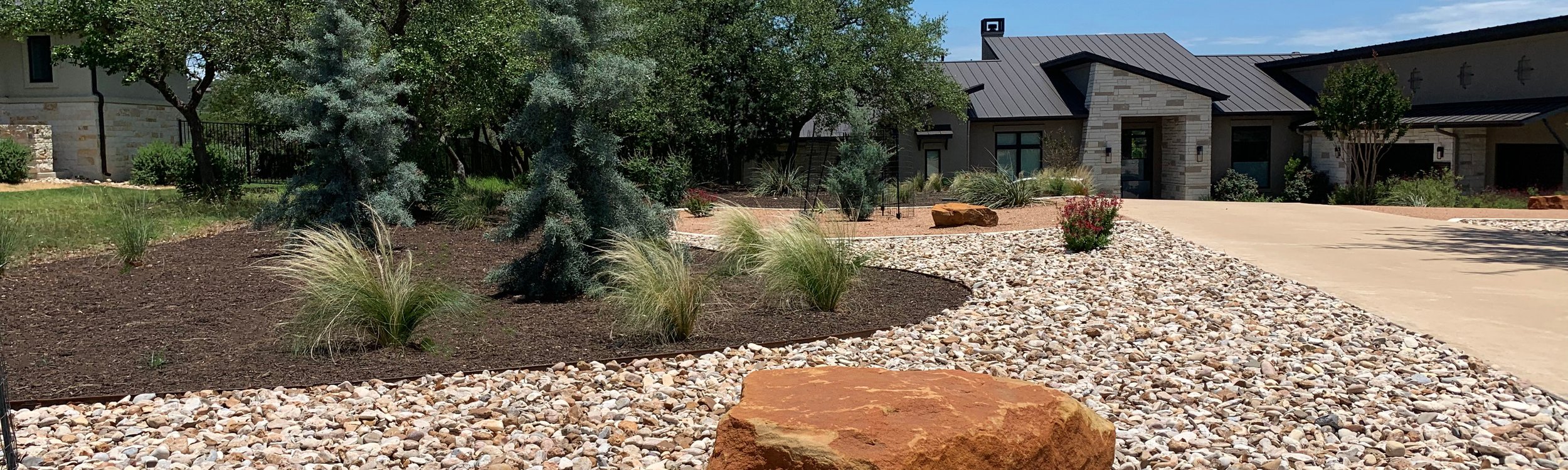 Dripping Springs Hill Country landscaping with river rock beds and drought-tolerant plantings