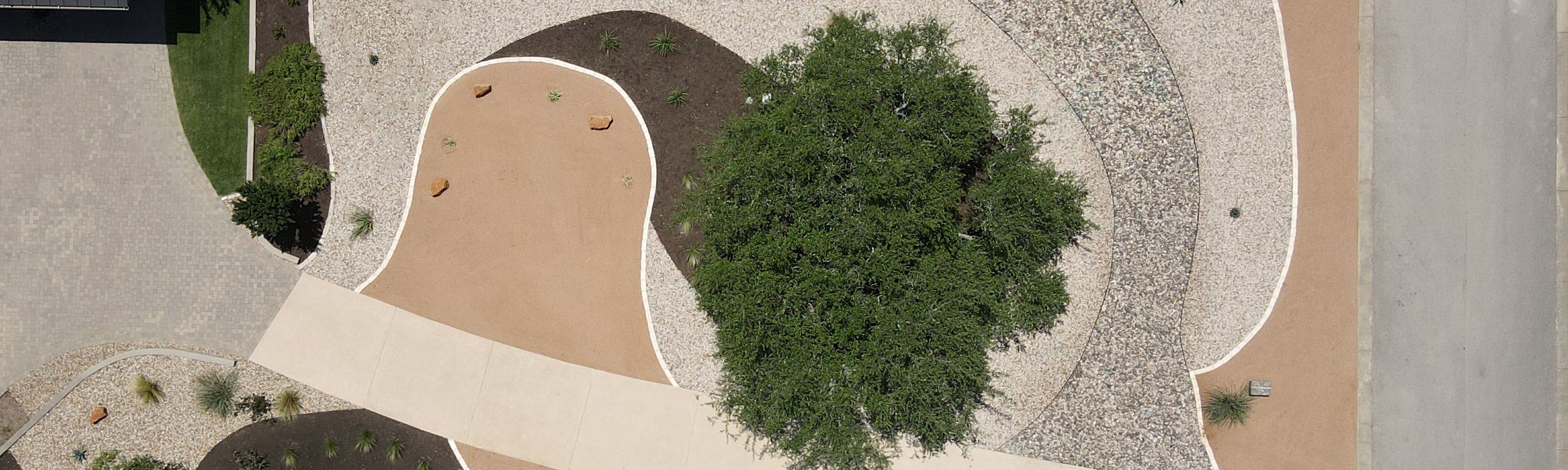 Dripping Springs drought-tolerant xeriscape with crushed granite, river rock, and native plants around a live oak