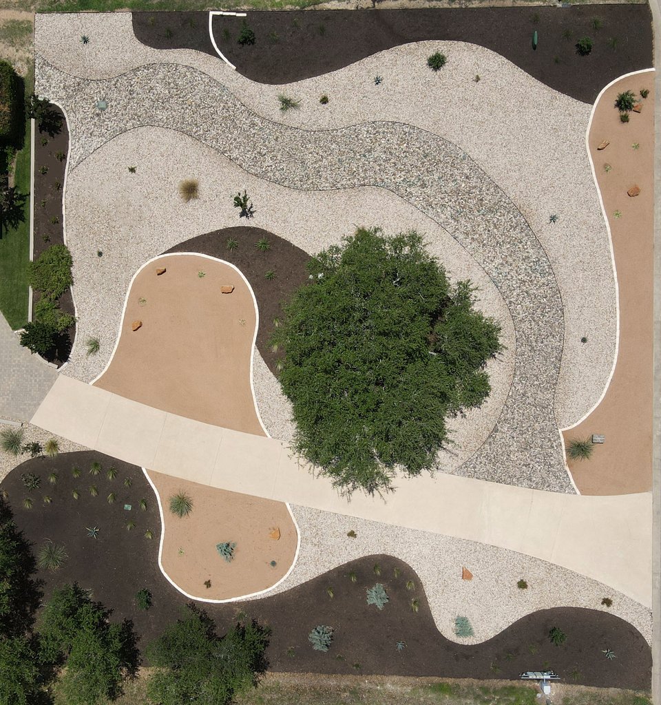 Aerial view of a Dripping Springs lawn-free native xeriscape with crushed granite, river rock, and mulch zones around a live oak