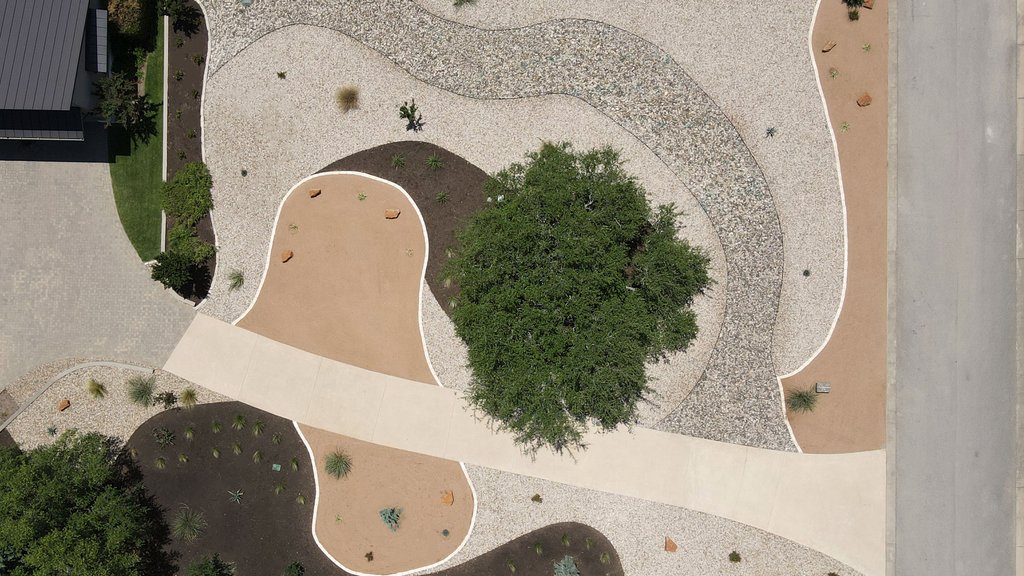 Designed Dripping Springs xeriscape with shaped grades and rock that route water through the yard