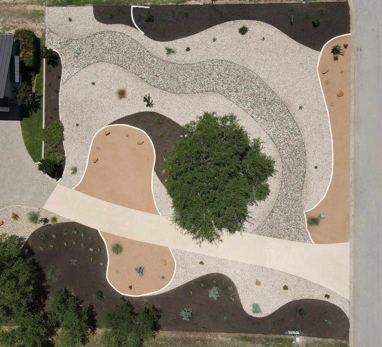 Aerial view of a Dripping Springs lawn-free native xeriscape with crushed granite, river rock, and mulch zones around a live oak